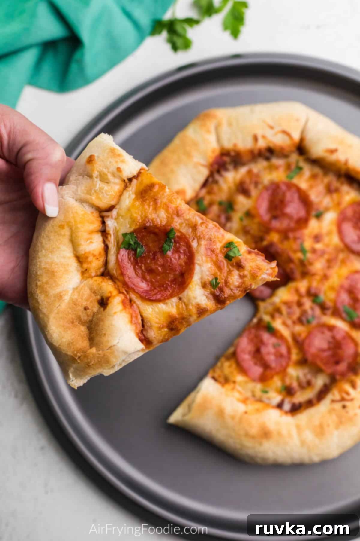 Crispy Air Fryer Pizza 9 A delicious slice of Air Fryer pizza held up, showcasing its crispy crust and perfectly melted toppings.