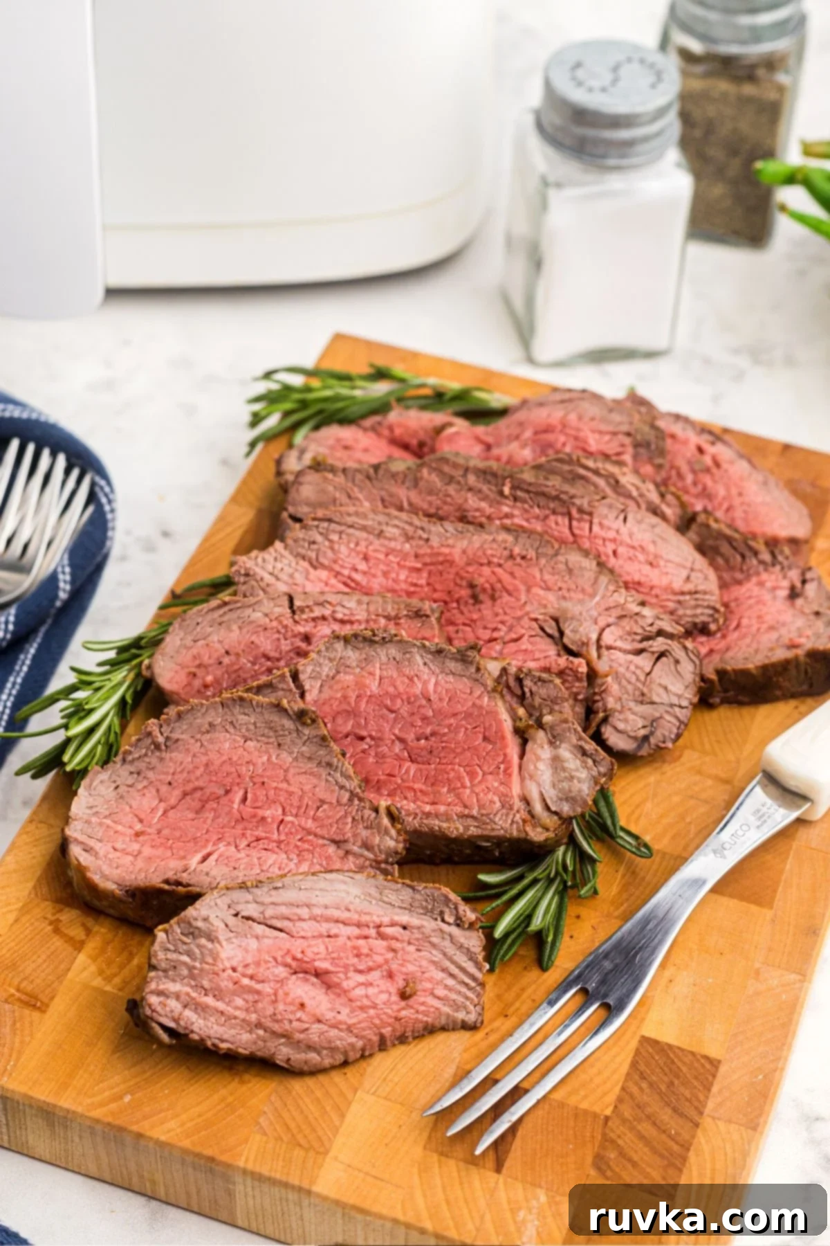 Perfect Air Fryer Beef Tenderloin 2 Juicy cuts of tenderloin on a cutting board after being cooked in the air fryer basket.