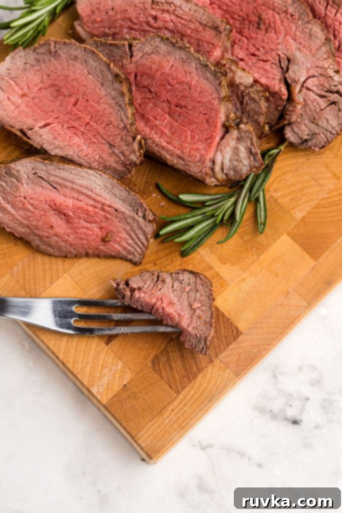 Perfect Air Fryer Beef Tenderloin 9 Juicy tenderloin on a cutting board with a piece on a serving fork.