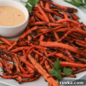 Crispy Air Fryer Carrot Fries 9 Carrot fries made in the air fryer and served on a plate with dipping sauce.