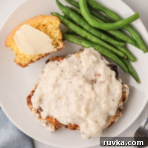 Crispy Air Fryer Chicken Fried Steak 10 Overhead shot of chicken fried steak made in the air fryer and served on a plate covered in gravy and served with green beans and a side of cornbread.