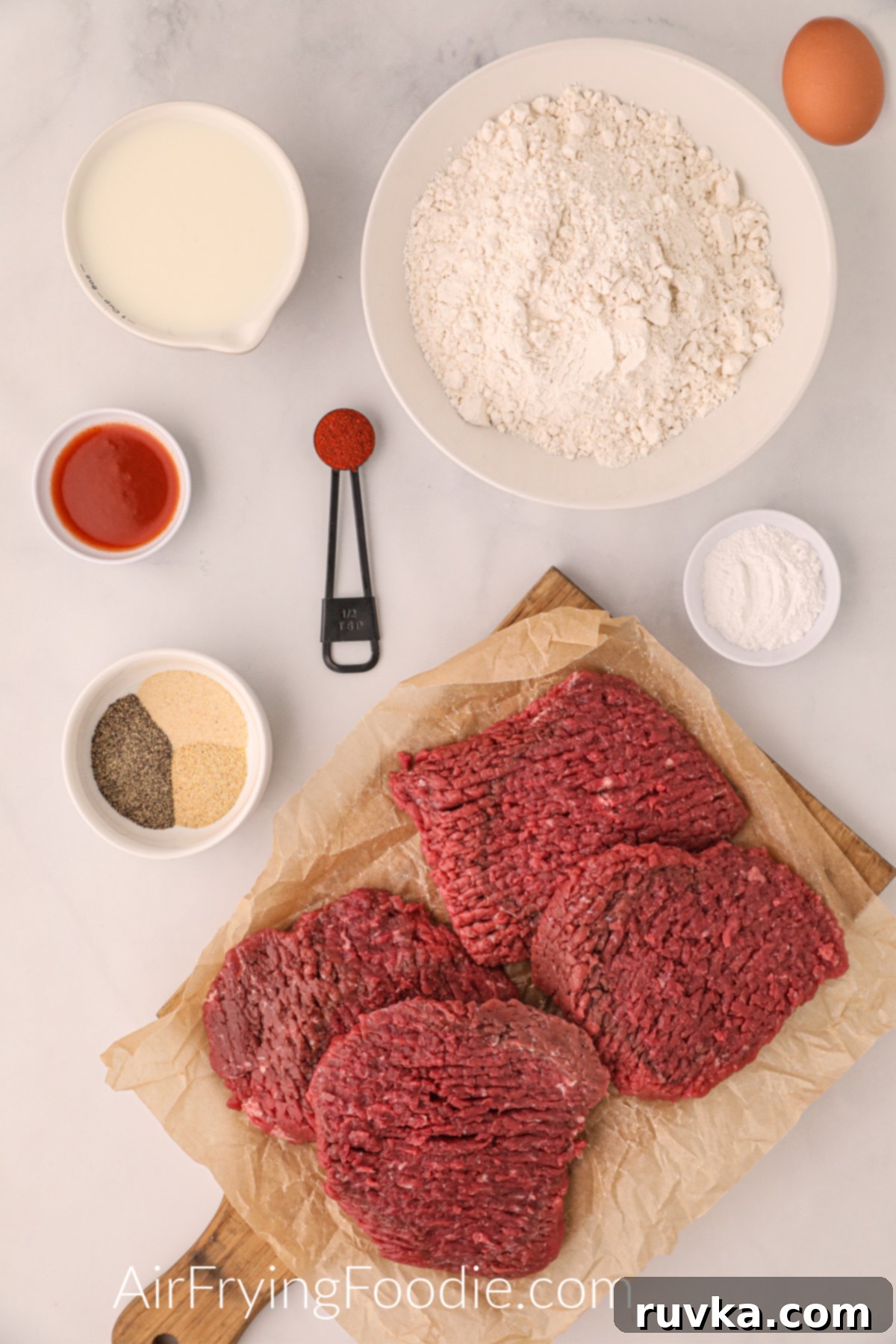 Crispy Air Fryer Chicken Fried Steak 3 Ingredients needed to make chicken fried steak in the air fryer, including cube steaks, flour, eggs, milk, hot sauce, and various spices.