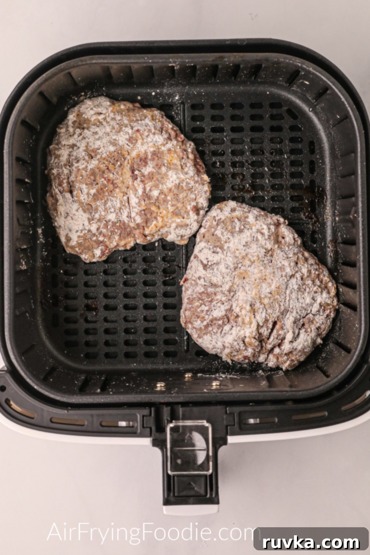 Crispy Air Fryer Chicken Fried Steak 6 Breaded round steaks placed in the basket of the air fryer, ready to cook.