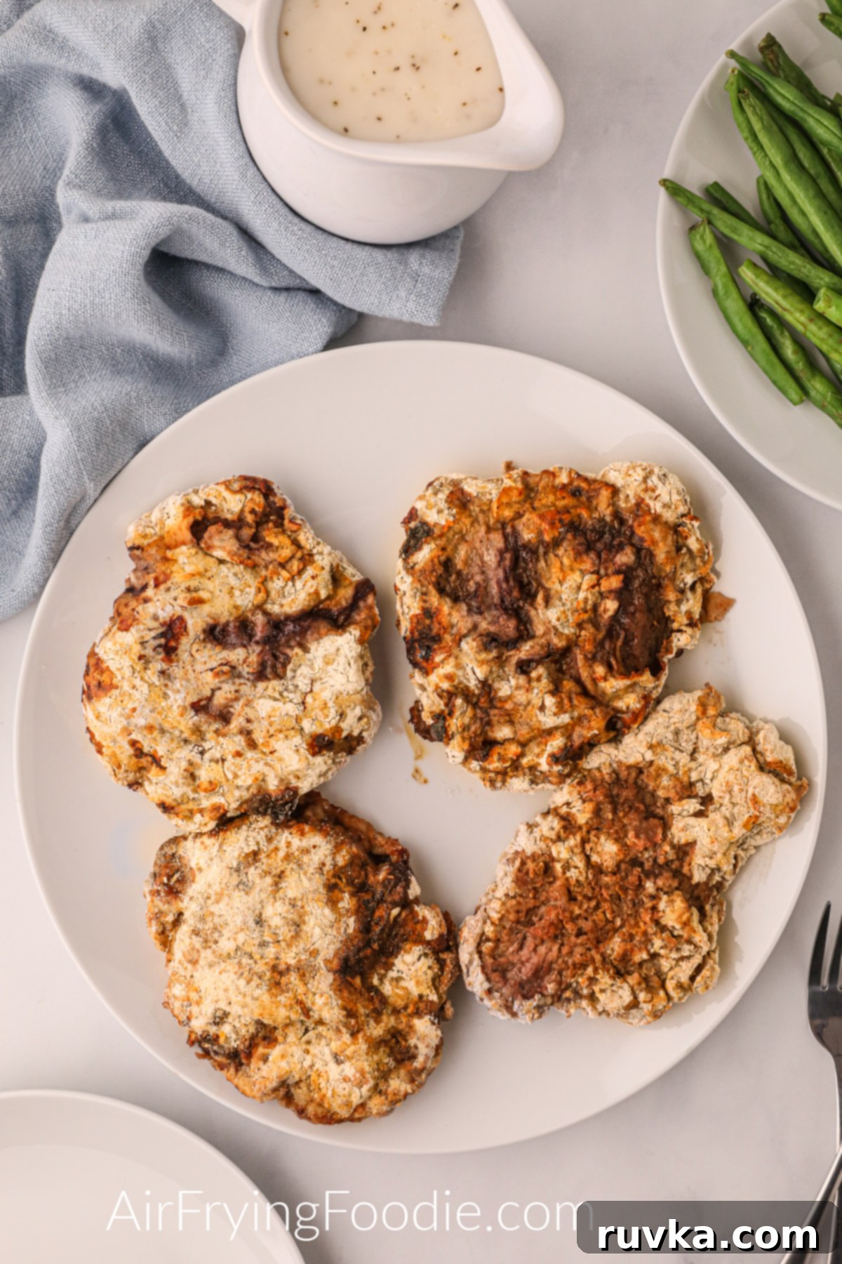Crispy Air Fryer Chicken Fried Steak 8 Air fryer chicken fried steaks served on a white plate with no sides.