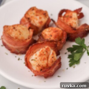 Crispy Air Fryer Bacon Wrapped Scallops 9 Bacon wrapped scallops on a white plate made in the air fryer.