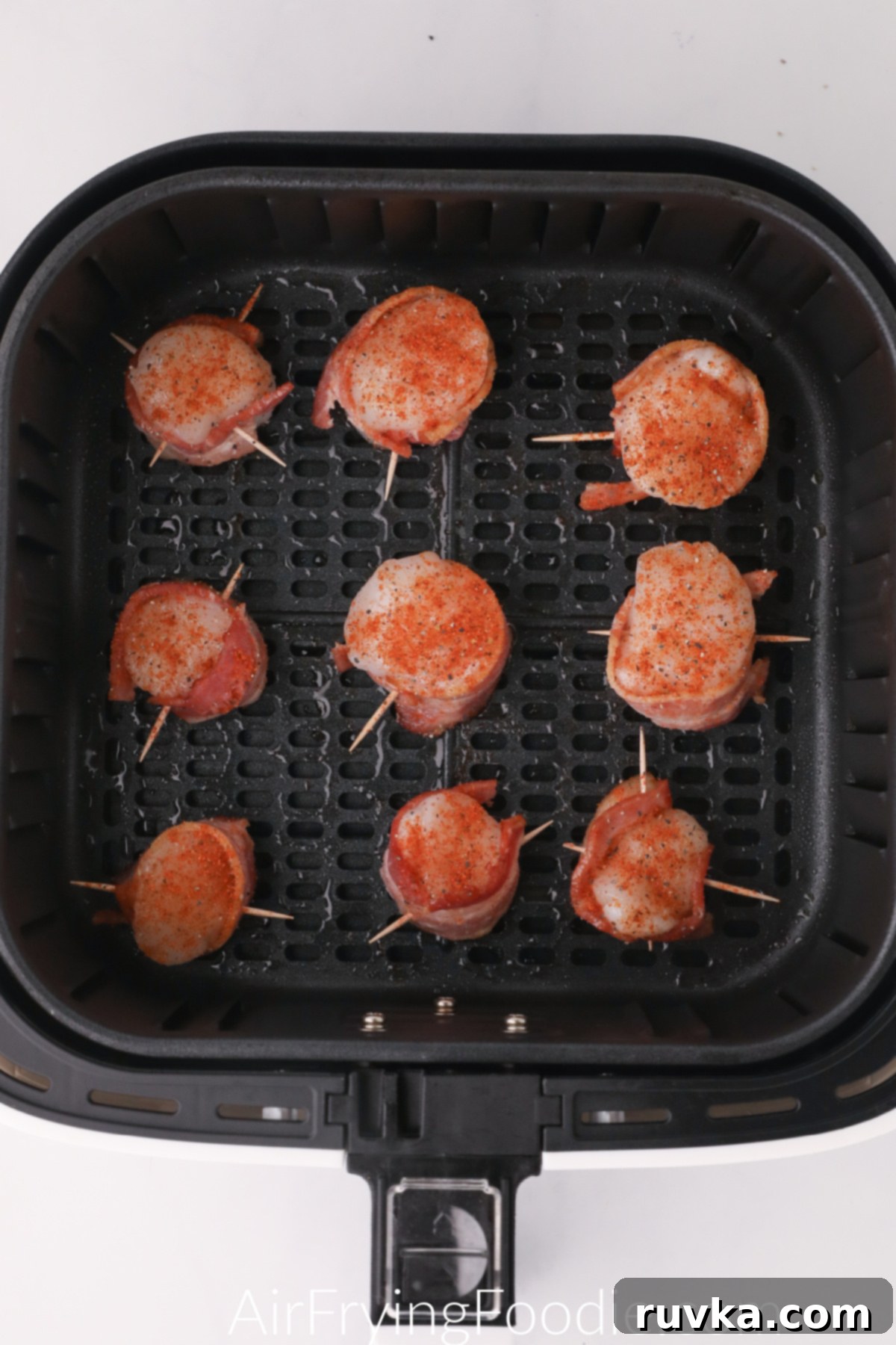 Crispy Air Fryer Bacon Wrapped Scallops 5 scallops wrapped in bacon and placed in a single layer in the basket of the air fryer.