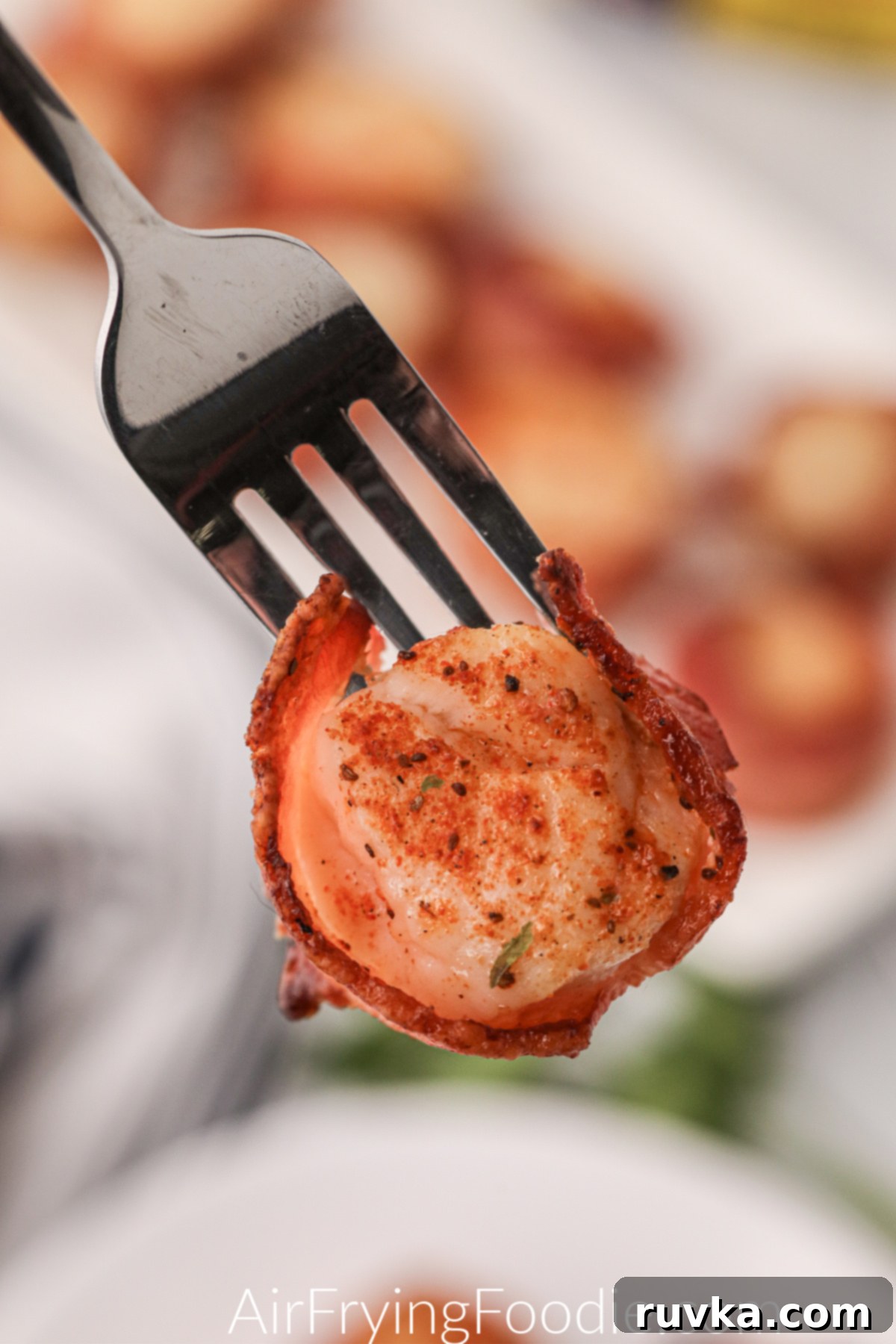 Crispy Air Fryer Bacon Wrapped Scallops 8 Fork holding an air fried bacon wrapped scallop and ready to eat.