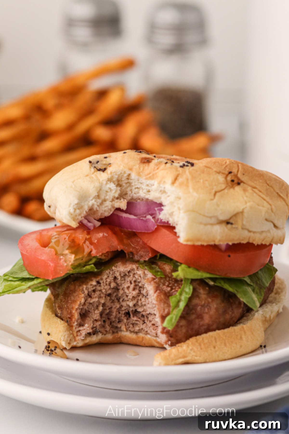 Crispy Air Fryer Turkey Burgers 7 Dressed air fryer turkey burger on a white plate, missing a bite.