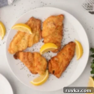 Perfectly Crispy Air Fryer Catfish 10 Air fried catfish on a white plate with lemon wedges.