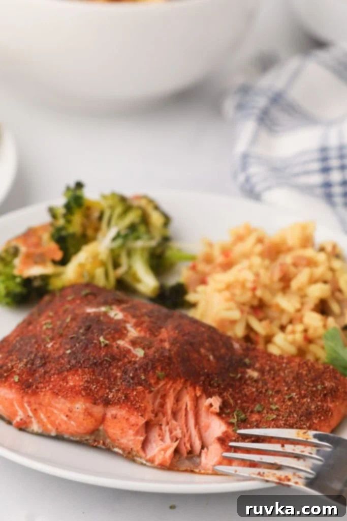 Crispy Air Fryer Salmon 2 Flaky cooked salmon on a white plate with rice and broccoli
