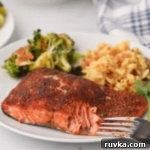 Crispy Air Fryer Salmon 8 Flaky seasoned salmon on a white plate with rice and broccoli with a fork bite