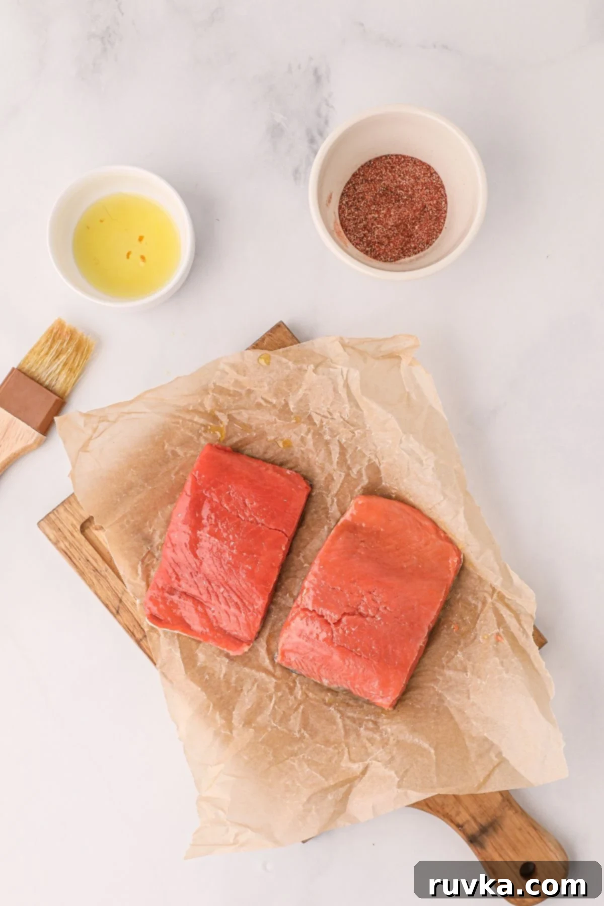 Crispy Air Fryer Salmon 4 Salmon on a board with seasonings mixed on the table with a brush and oil