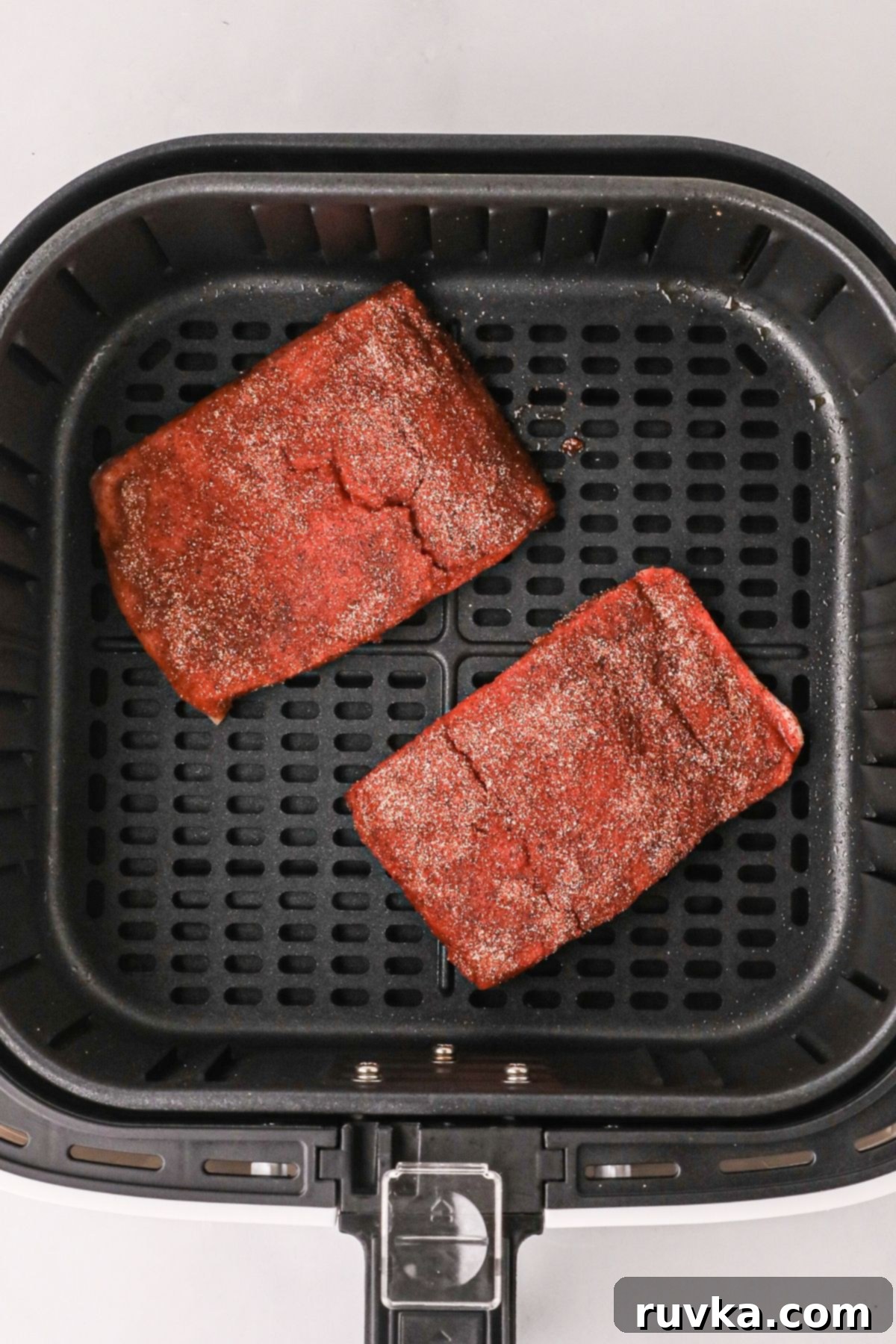 Crispy Air Fryer Salmon 5 Seasoned filets in an air fryer basket before being cooked
