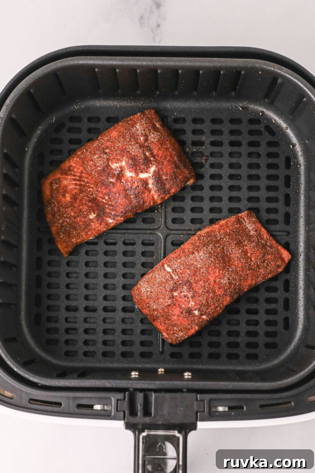 Crispy Air Fryer Salmon 6 Seasoned salmon filets in the air fryer basket after being cooked