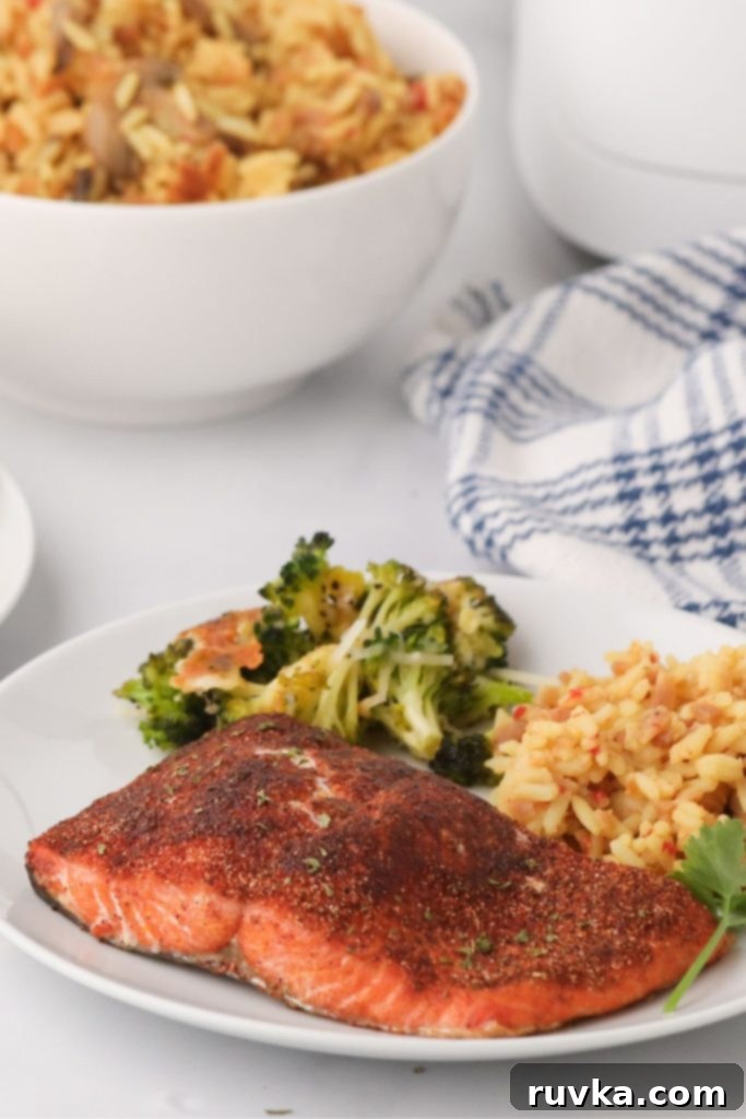 Crispy Air Fryer Salmon 7 Seasoned cooked salmon on a white plate with rice and broccoli