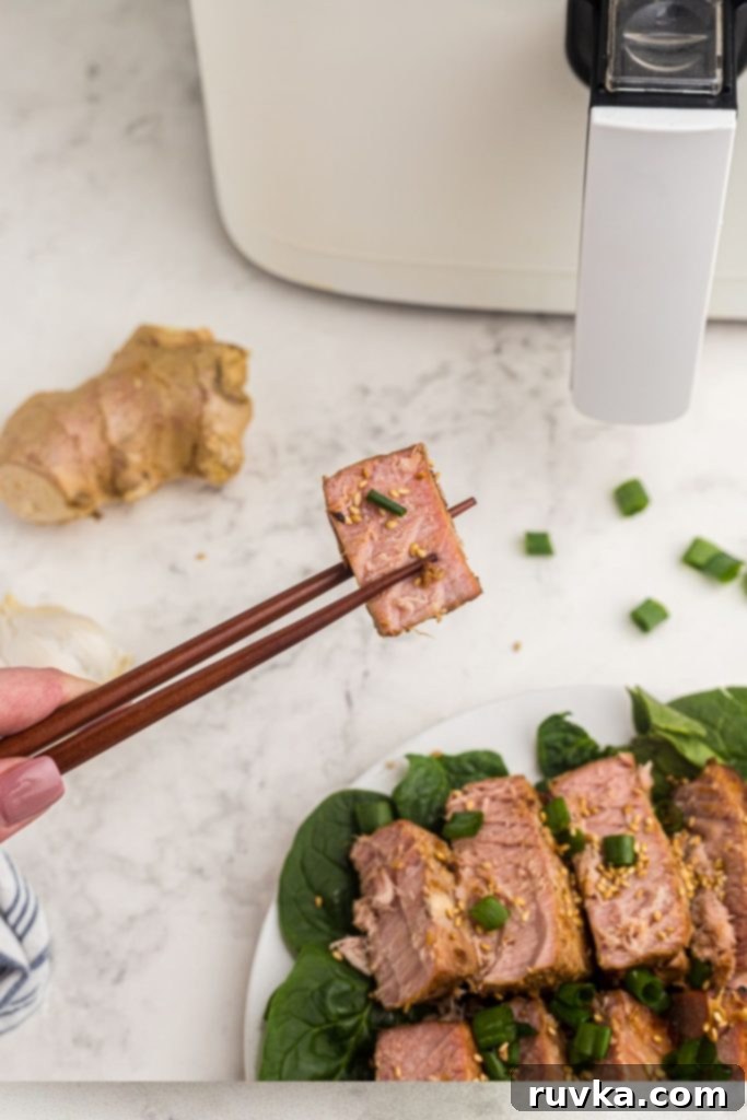 Crispy Air Fryer Tuna Steaks 7 Chopsticks holding a piece of tuna steak garnished with sesame seeds