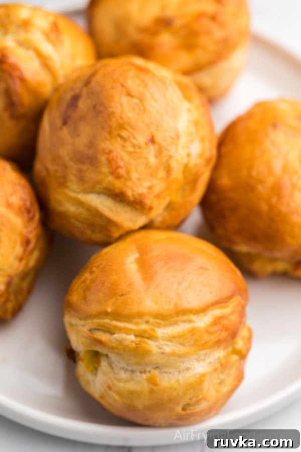 Air Fryer Biscuit Surprises 5 Biscuit Bombs stuffed with cheese, egg, and bacon on a white plate. The golden crust is visible.