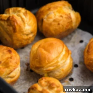 Air Fryer Biscuit Surprises 6 Air Fryer Biscuit Bombs on parchment paper in the basket of the Air Fryer.