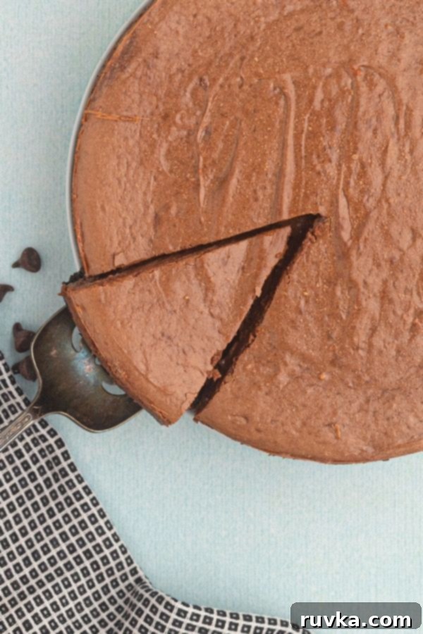 Decadent Air Fryer Chocolate Cheesecake 3 Air Fryer chocolate cheesecake with a slice cut, being lifted on a spatula.