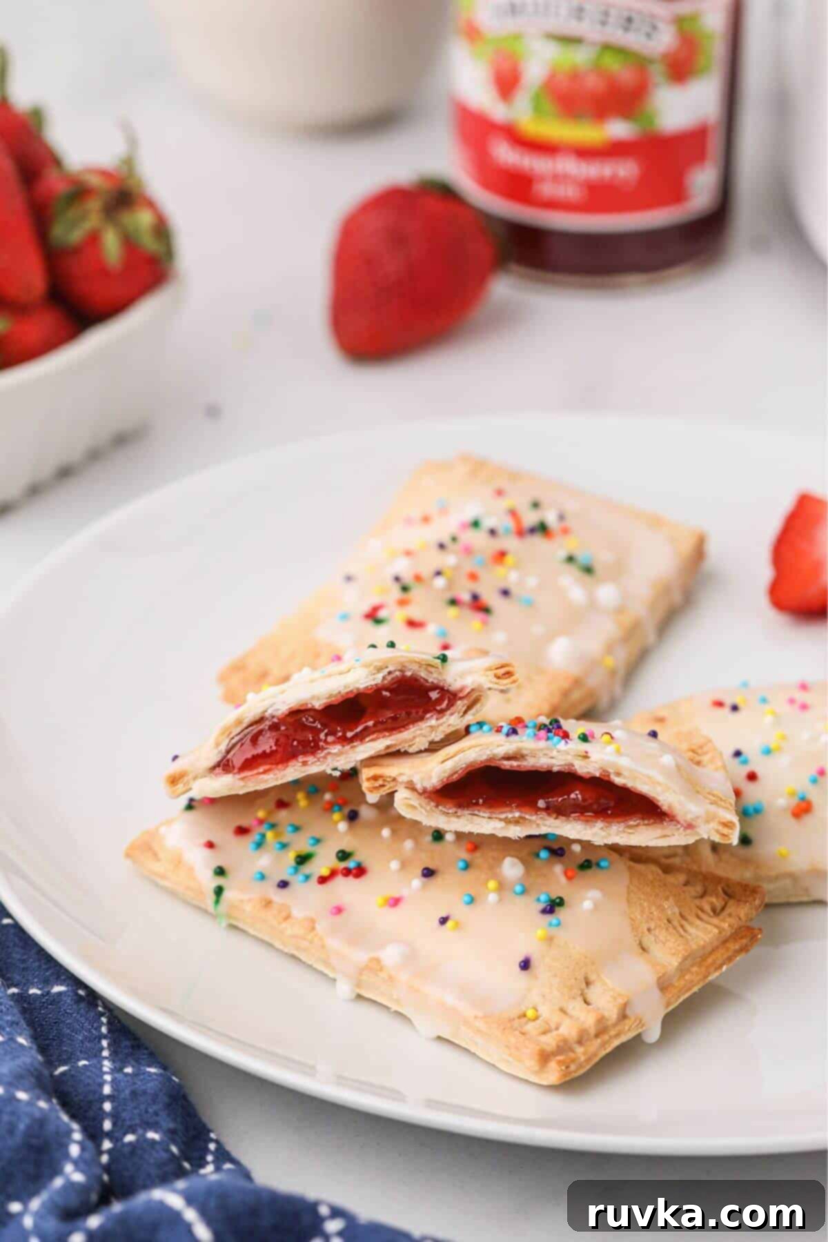 Air Fried Pop Tart Perfection 2 Crispy golden brown crusted pastries filled with strawberry jam and frosted, on a white plate.