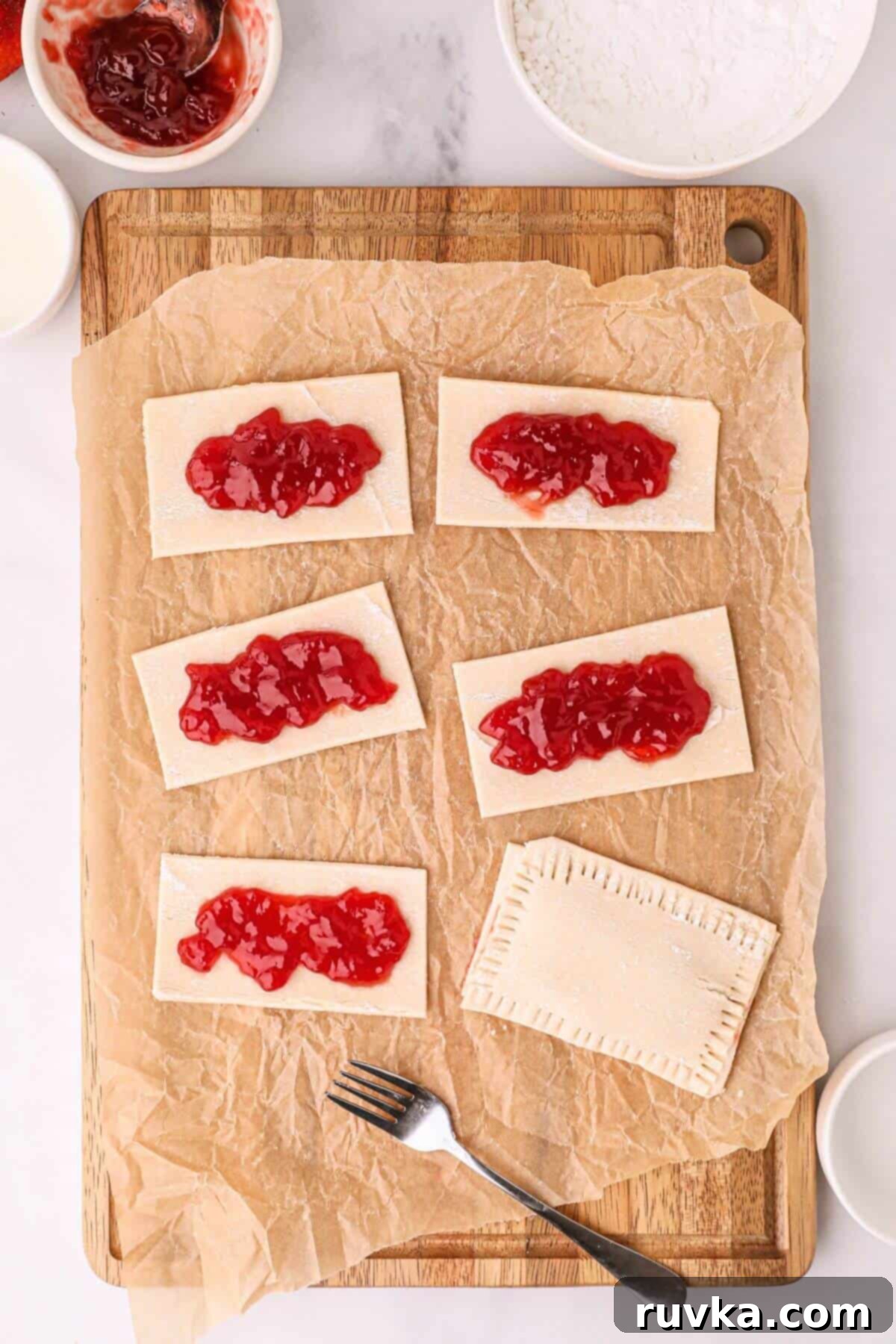 Air Fried Pop Tart Perfection 5 Rectangles of pastries on a wooden cutting board topped with jam.