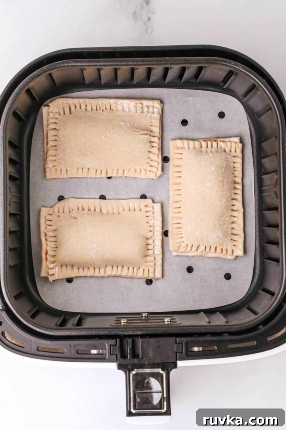Air Fried Pop Tart Perfection 7 Uncooked pastry filled with jam in the air fryer basket.