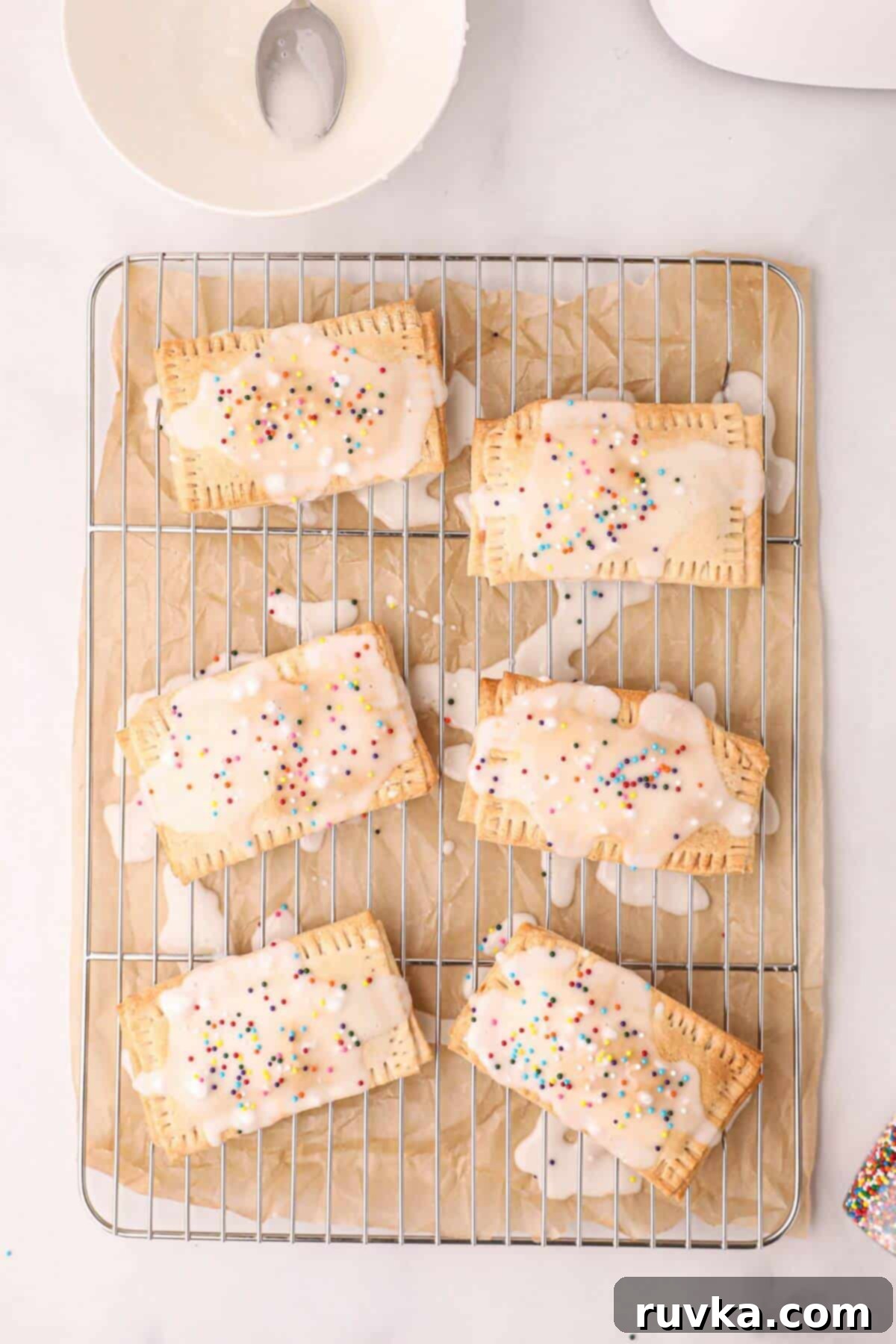 Air Fried Pop Tart Perfection 9 Golden pastries drizzled with white glaze and sprinkles on a cooling rack.
