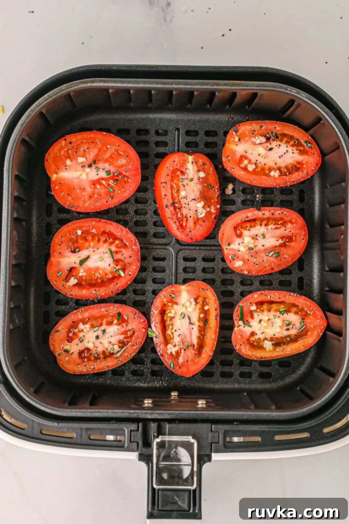 Air Fryer Roasted Tomatoes 6 uncooked tomatoes in the air fryer basket before being cooked.