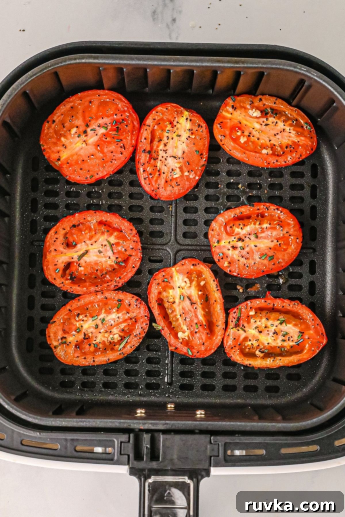 Air Fryer Roasted Tomatoes 7 Cooked tomatoes in the air fryer basket after being seasoned.