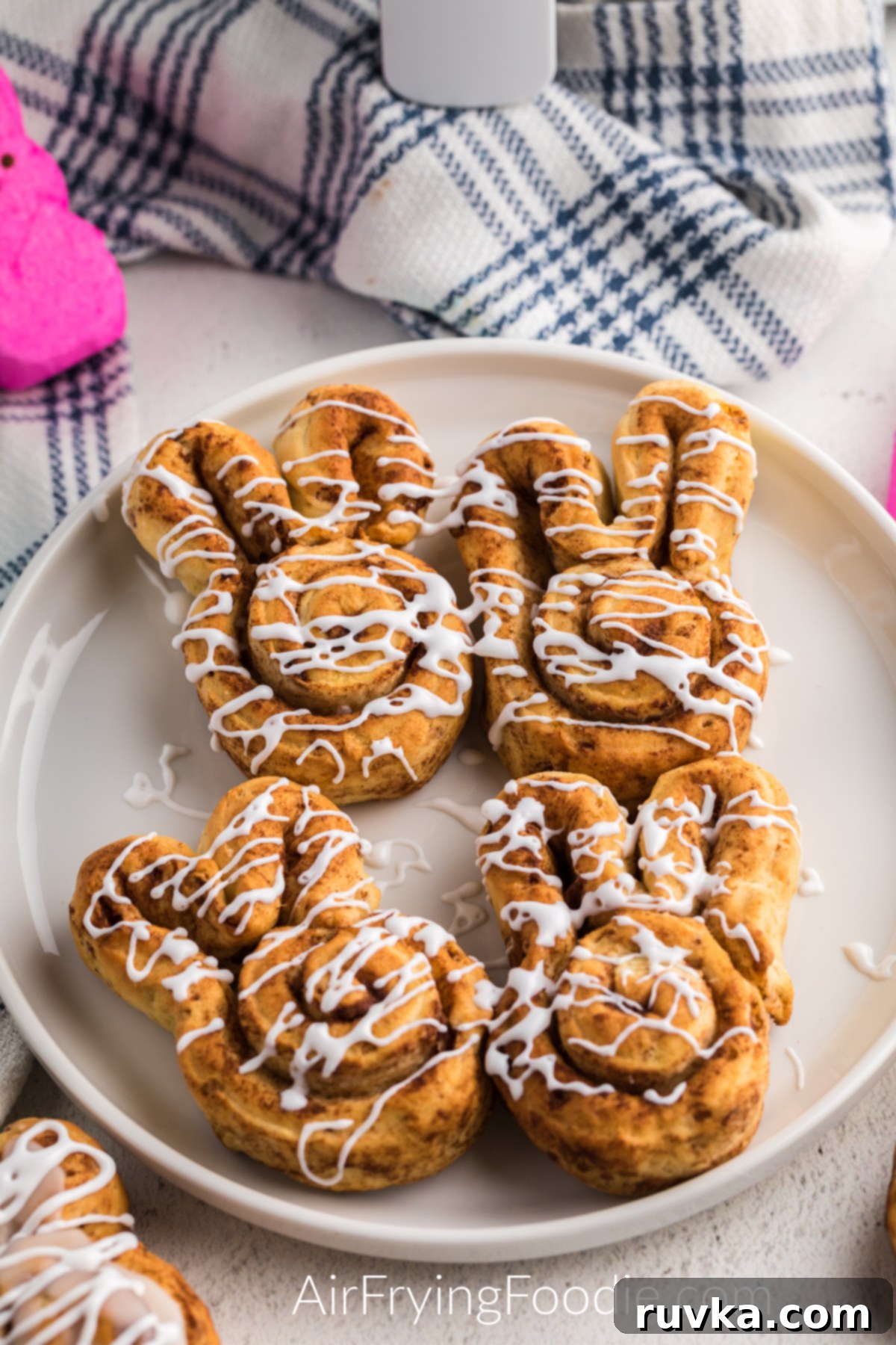 Air Fryer Cinnamon Bunny Delights 2 Air Fryer Cinnamon Roll Bunnies on a pristine white plate, freshly baked and beautifully glazed, ready to be served for breakfast or a sweet snack. Each bunny is perfectly golden with delicate ears.