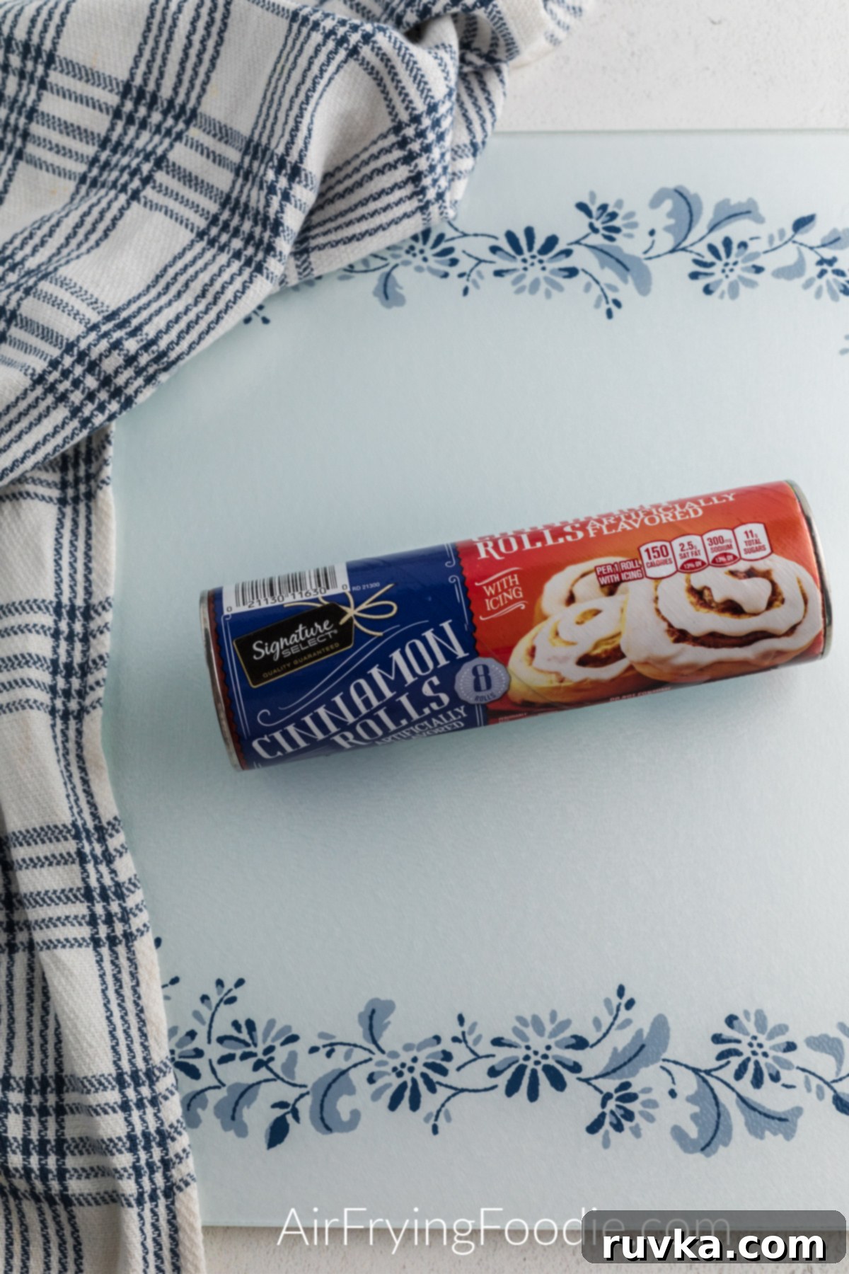 Air Fryer Cinnamon Bunny Delights 3 An unopened can of refrigerated cinnamon rolls rests on a wooden cutting board, ready for crafting into Air Fryer Cinnamon Roll Bunnies.