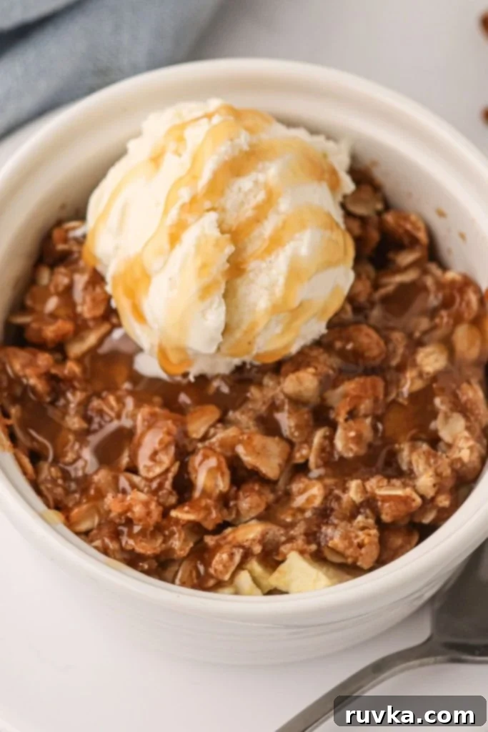 Easy Air Fryer Apple Crisp 2 Close up photo of apple crisp topped with oats and ice cream, drizzled in caramel sauce.
