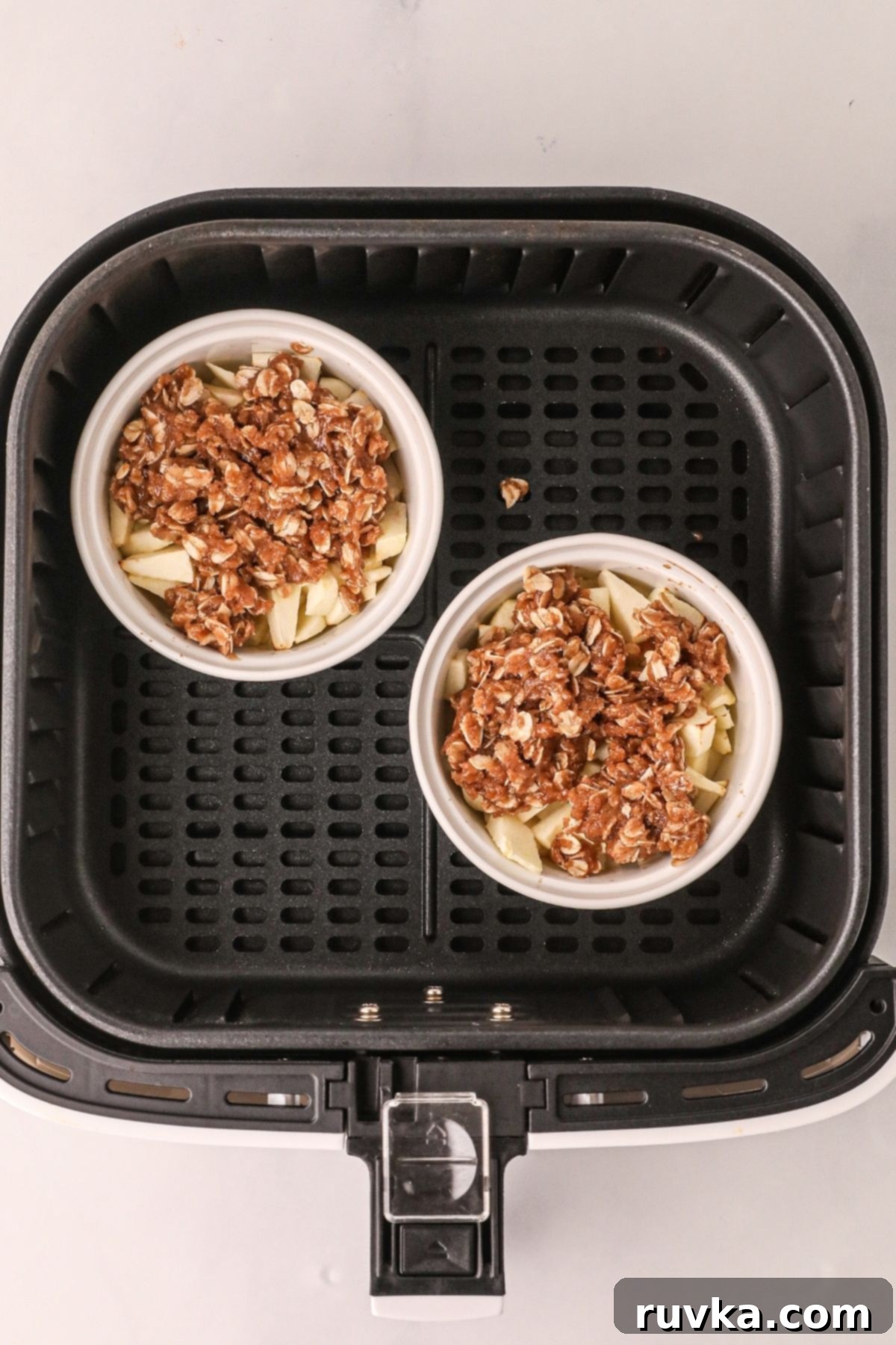 Easy Air Fryer Apple Crisp 6 Cooked apple mixture in white ramekins topped with oat mixture