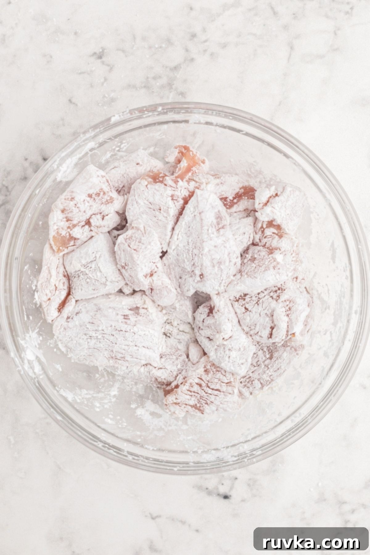 Crispy Air Fryer Sweet & Tangy Chicken 4 Chicken coated with cornstarch in a clear glass bowl