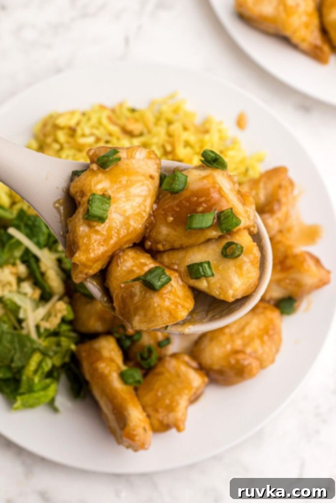 Crispy Air Fryer Sweet & Tangy Chicken 9 Spoonful of sweet and sour chicken being served over a white plate