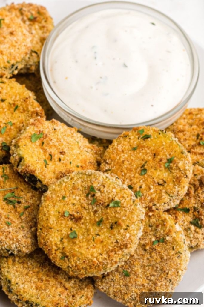 Crispy Air Fryer Zucchini Crisps 9 Crispy golden zucchini chips on a white plate with various dipping sauces