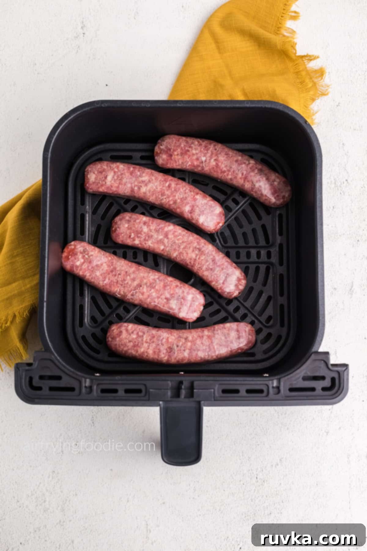 Crispy Air Fryer Italian Sausage 3 Italian sausage in air fryer basket in a single layer, ready to be cooked.