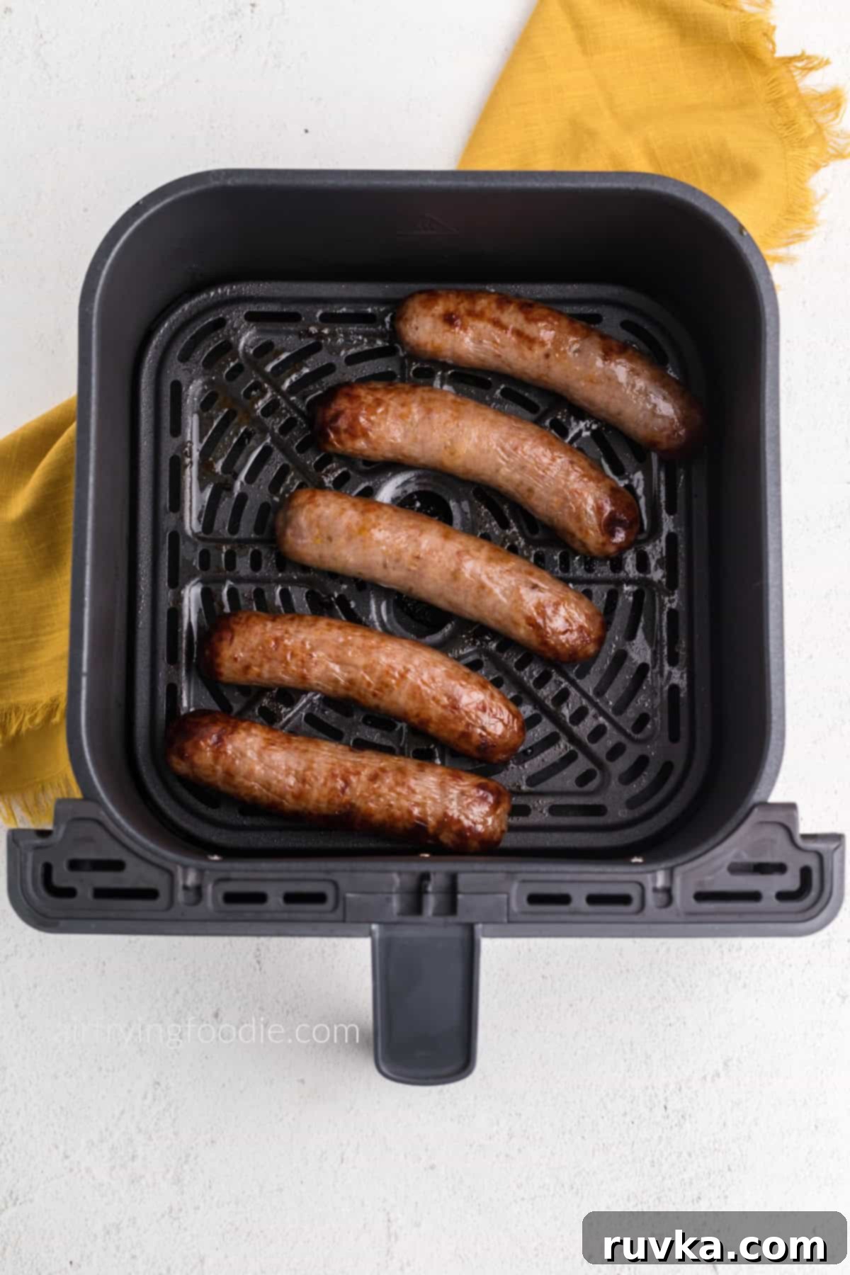 Crispy Air Fryer Italian Sausage 4 Italian sausage in basket of the air fryer, fully cooked and ready to serve.