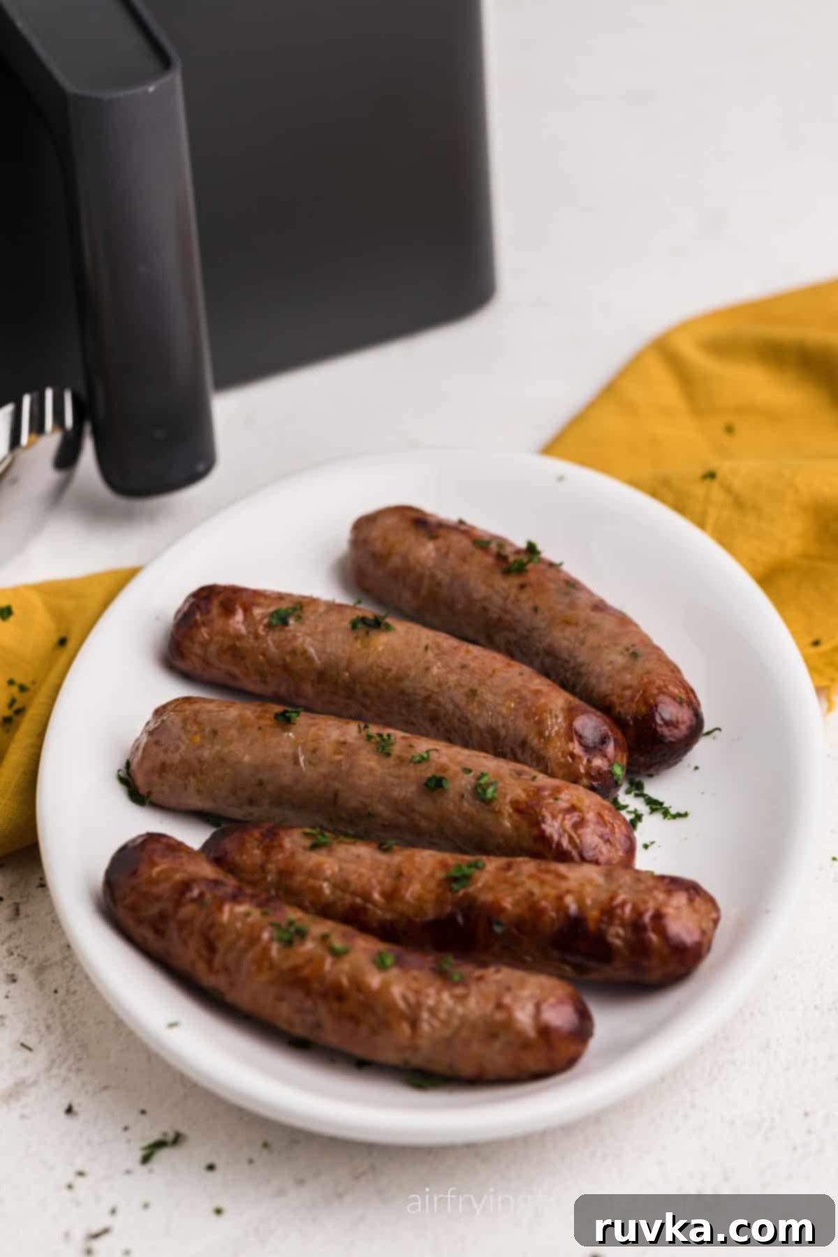 Crispy Air Fryer Italian Sausage 6 Italian sausages made in the air fryer, served on a white platter with parsely garnish on top.