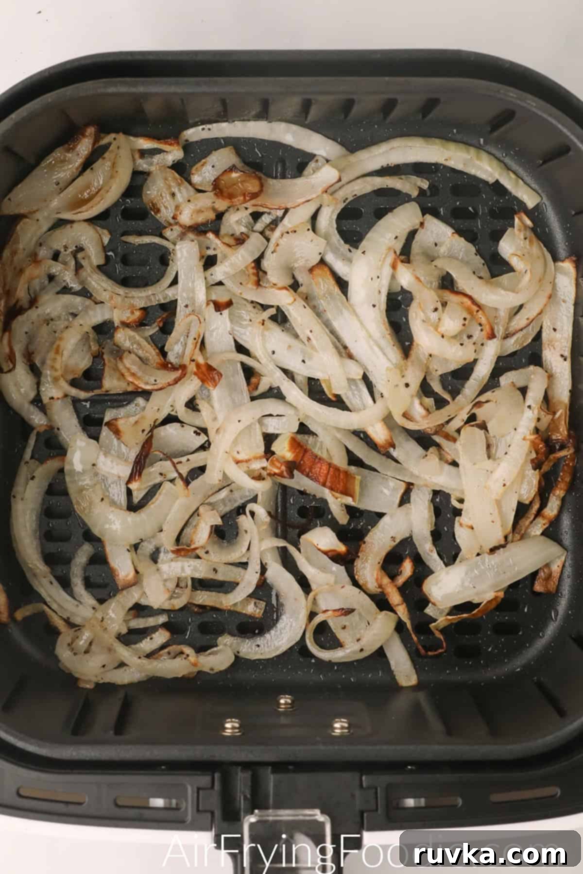 Crispy Air-Fried Onions 2 Crispy cooked air fryer onions in the basket of the air fryer, ready to serve.