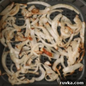 Crispy Air-Fried Onions 9 Crispy air fried onions in the basket of the air fryer.