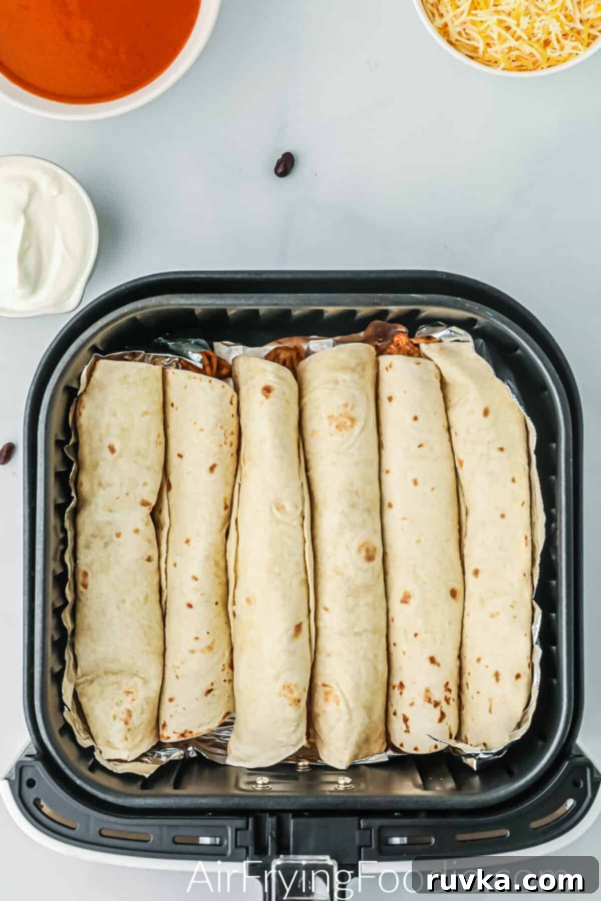 Easy Air Fryer Enchiladas 6 Enchiladas rolled and placed into the air fryer basket.