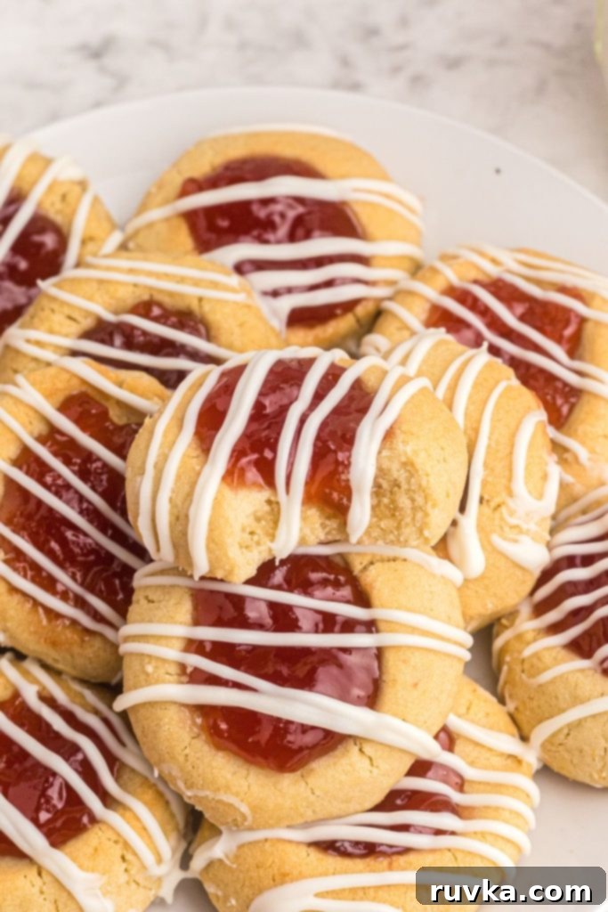 Quick Air Fryer Thumbprint Cookies 2 Close up photo of thumbprint cookies with strawberry jam on top drizzled with melted white chocolate