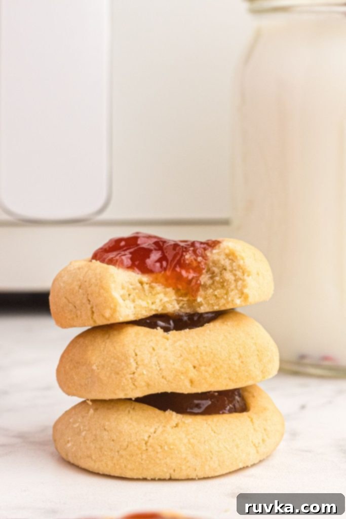 Quick Air Fryer Thumbprint Cookies 10 Three cookies stacked on a white marble table in front of the air fryer
