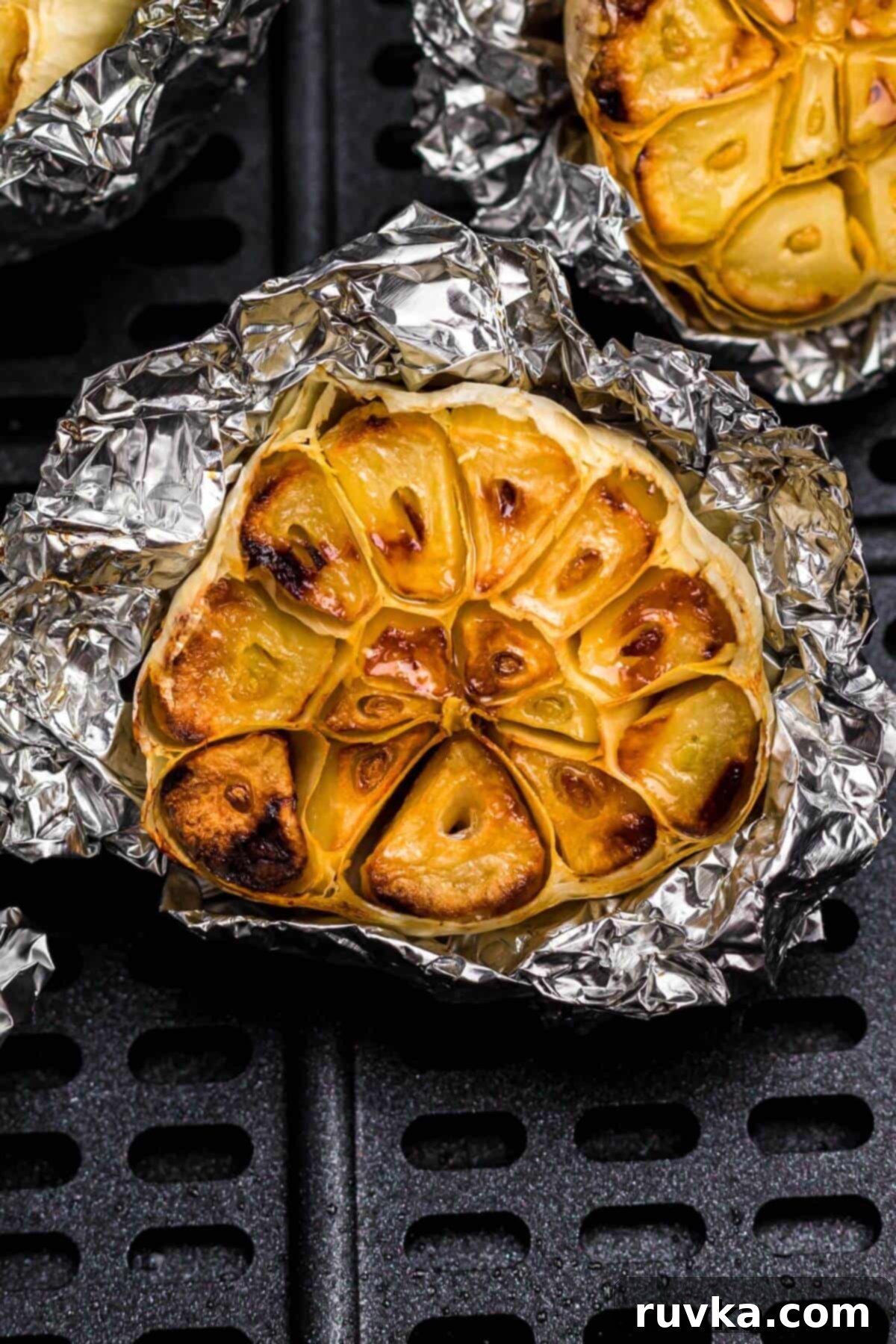 Perfect Air Fryer Roasted Garlic 2 Golden roasted garlic on a piece of foil in the air fryer basket.