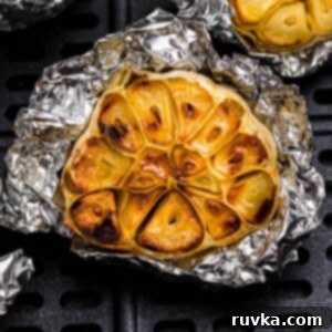 Perfect Air Fryer Roasted Garlic 8 Golden roasted garlic on a piece of foil in the air fryer basket.