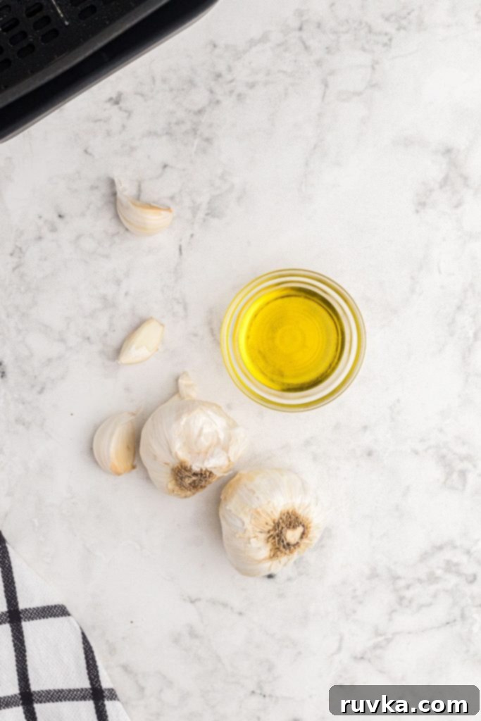 Perfect Air Fryer Roasted Garlic 3 Garlic bulbs and olive oil on a white marble talble