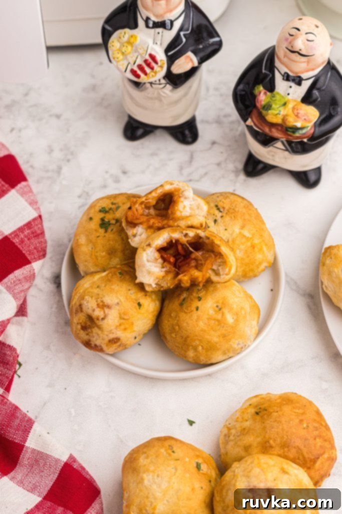 Air Fryer Pizza Poppers 2 Golden crusted pizza bombs on a white small plate on a marble table