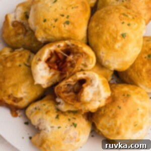 Air Fryer Pizza Poppers 9 Golden biscuits filled with pizza toppings stacked on a white plate