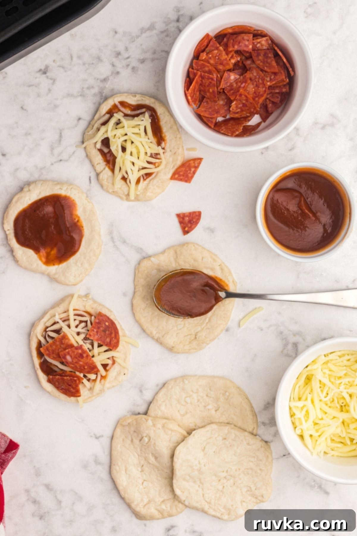 Air Fryer Pizza Poppers 5 Spoonful of sauce, cheese, and pepperoni being placed in center of biscuit